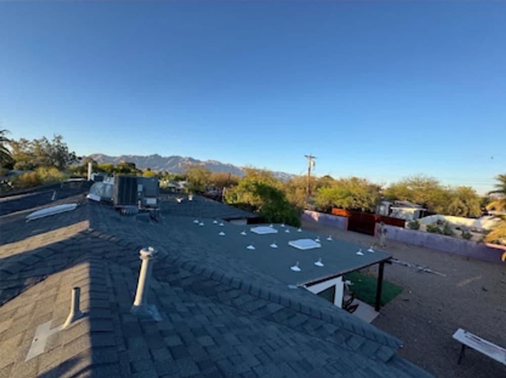 Roof view showing mountains and landscaping under clear blue sky. Ideal for real estate and home improvement.