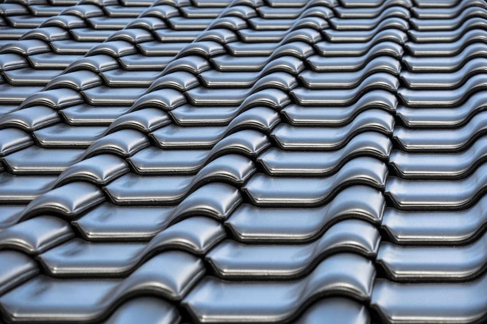 Close-up of a black corrugated metal roof with interlocking tiles for durability and style.